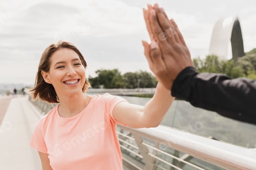 Preview: Young woman and man boyfriend and girlfriend friends giving high five after workout training