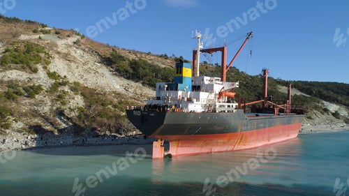 Preview: Aerial for an empty industrial ship moored near sea shore with many people walking on a beach