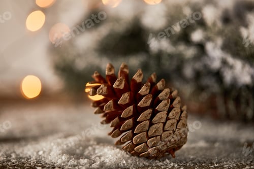 Preview: close up of pine cone on wooden table with spruce branches in snow and christmas lights bokeh