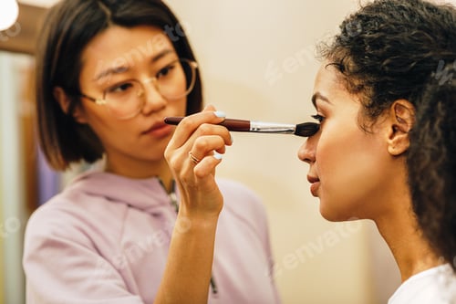 Preview: Close up of make up artist hand shading under the eyes of a model