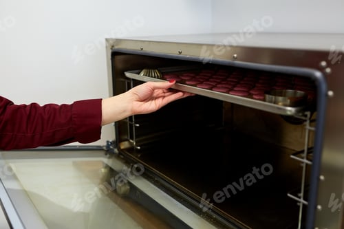 Preview: chef with macarons on oven tray at confectionery