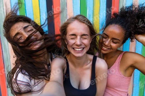 Preview: Young women taking selfie outdoors while wind blowing hair