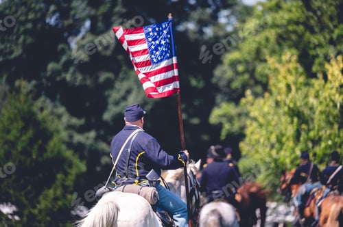 Preview: Veteran riding a horse and holding the USA flag reenacting the American Civil War.