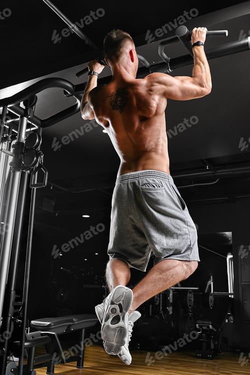 Preview: The athlete does pull-ups - chin in the gym, model with a sports body topless. Shot from the back