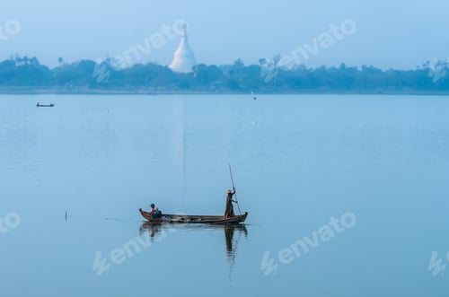 Preview: Fishermen fishing by traditional net on the boat in the river near U-Bein bridge in evening