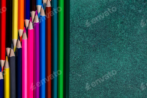 Preview: top view of colored pencils arranged on dark background with copy space