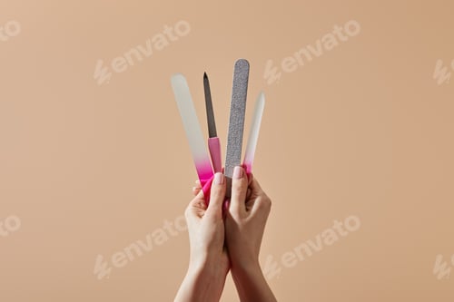 Preview: Cropped view of woman holding nail files and emery board isolated on beige