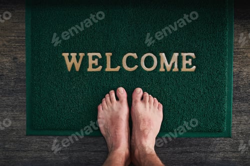 Preview: High angle shot of a mans bare feet standing on a welcome mat