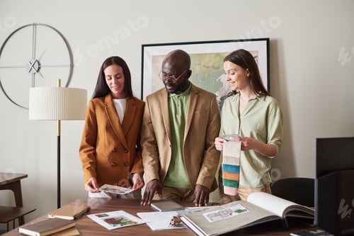 Preview: Three young intercultural designers looking at sketches or photos of interiors