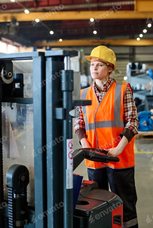 Preview: Female engineer looking forwards while standing in front of electric forklift