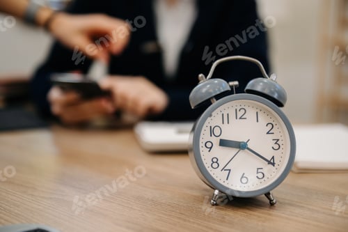 Preview: Alarm clock on the desk. Business working in modern office building or home at night using laptop.
