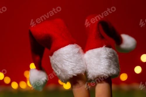 Preview: Fingers dressed in Santa-Claus red-white hats. Two happy finger representing social network on red