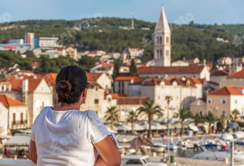 Preview: Girl looking at idyllic coastal town of Supetar on Brac island in Croatia in the summer