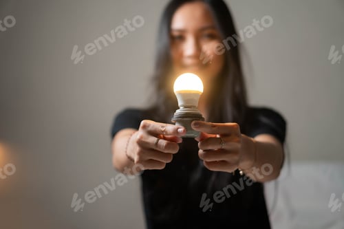 Preview: Woman holding a glowing LED light bulb
