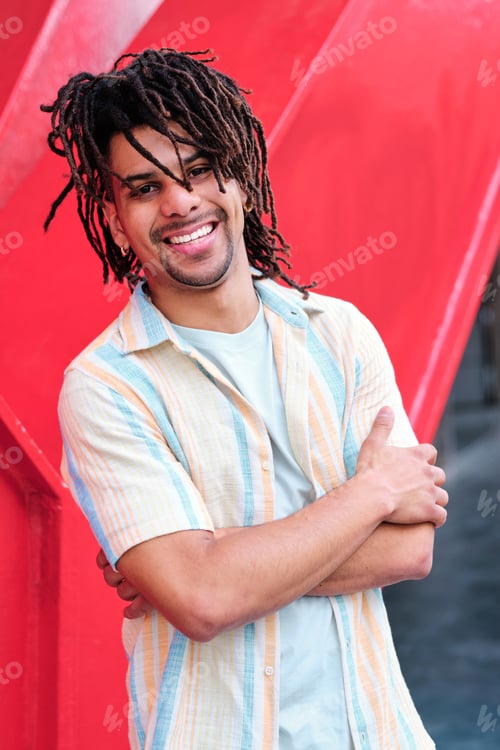 Preview: young confident latinx man with curly hairlooking at camera and smiling