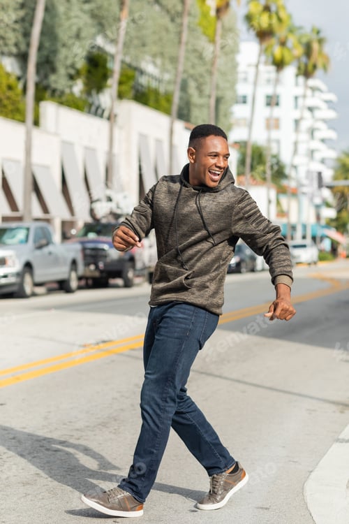 Preview: full length of overjoyed african american man in hoodie and jeans walking on street in Miami