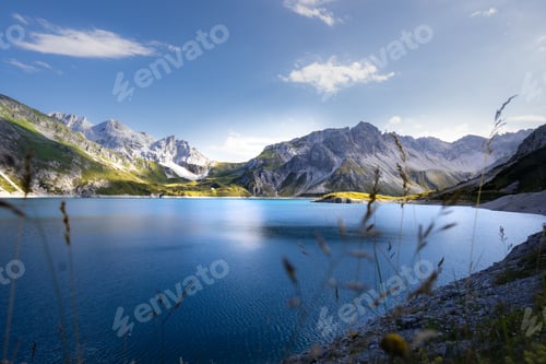 Preview: Tranquil Lunersee lake surrounded by lush green grass and jagged mountains in Austria