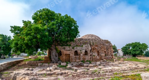 Preview: Ancient stone structure with tree under blue sky.
