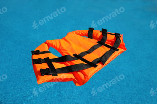 Preview: Bright orange life jacket floating in swimming pool