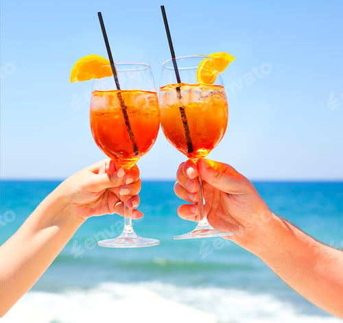 Preview: Two cocktail glasses in the hands on sea background