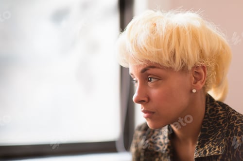 Preview: A young woman with blonde hair looking out of the window.