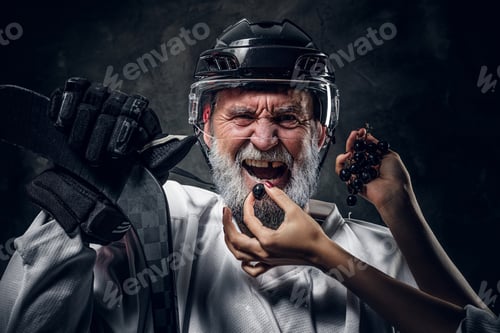 Preview: Woman feeding elderly hockey player against dark background