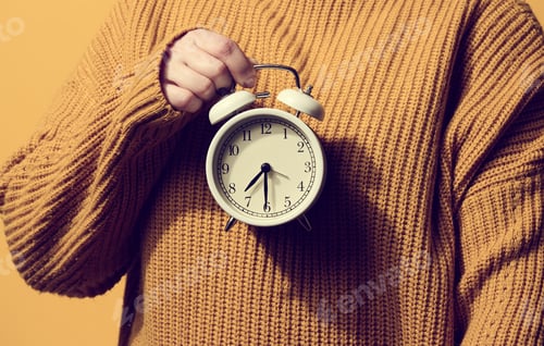 Preview: Round alarm clock in a woman's hand, the time is half past seven in the morning
