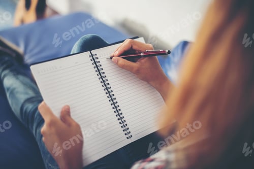Preview: Woman hands writing on notepad lying at home .