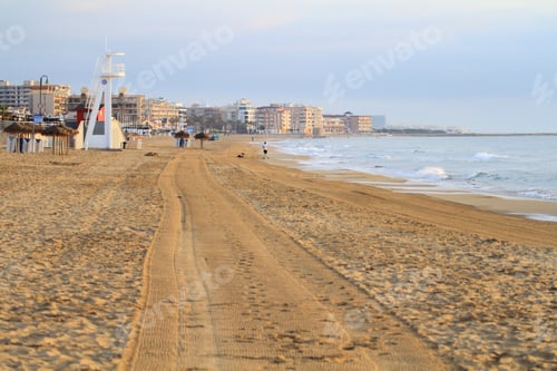 Preview: a sandy beach near the ocean with people walking along it