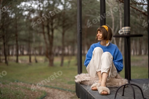 Preview: Woman rests near wooden cottage in nature