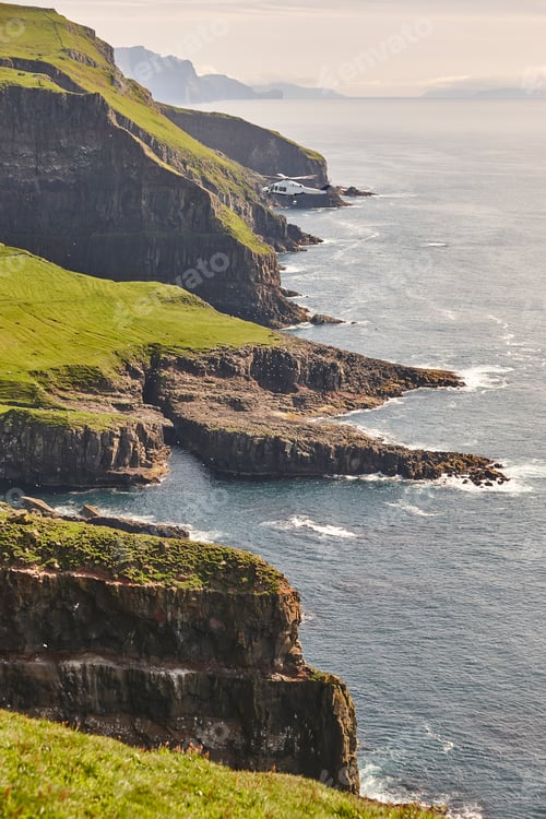 Preview: Helicopter flying over mykines atlantic cliffs in Faroe islands. Transportation