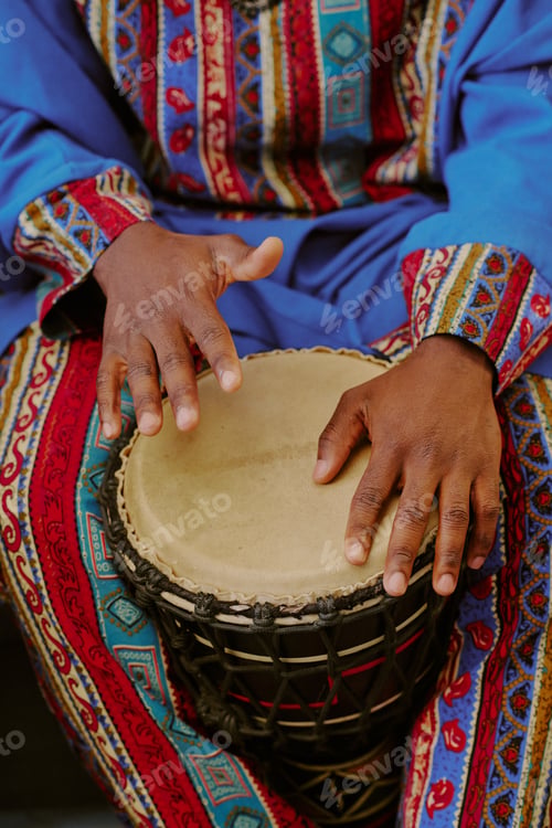 Preview: Black Adult Playing Drum during Kwanzaa Celebration in Traditional Clothing
