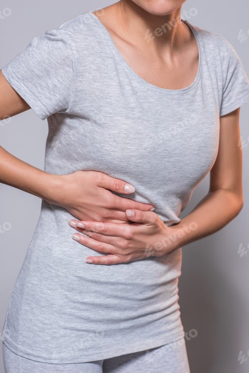 Preview: partial view of woman having liver ache on grey background