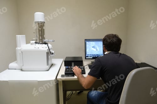 Preview: Young man scientist working with scanning electron microscope