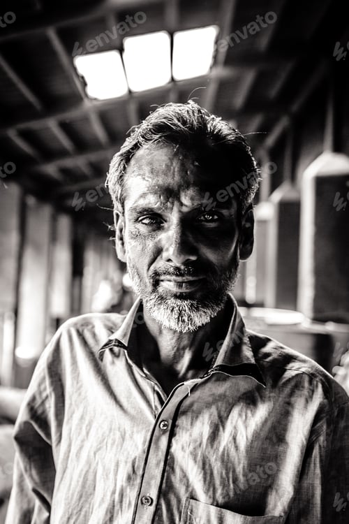 Vorschau: Mann in einem Gebäude in Mumbai, der Blickkontakt mit der Kamera in Indien herstellt, in Graustufen