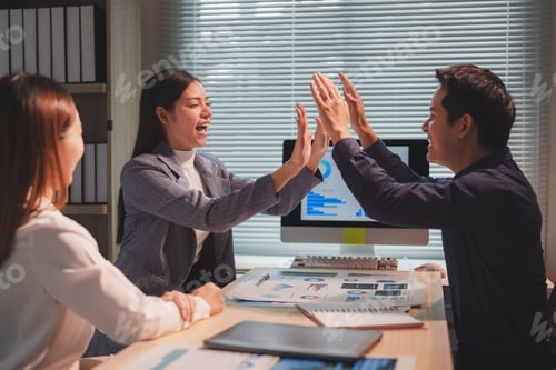 Preview: Happy business team giving high five after successful presentation in office meeting