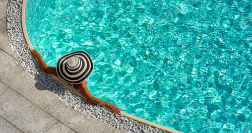 Preview: Person relaxing by the crystal clear poolside in summer