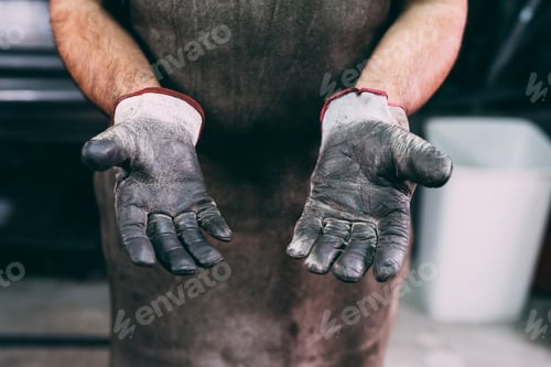Preview: Mid section of metalworker's protective gloves in forge workshop