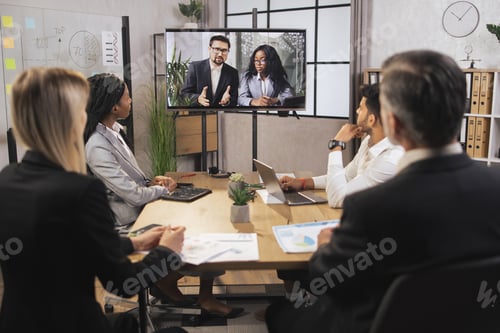 Preview: Team of diverse four multiethnic businesspeople having video meeting in boardroom