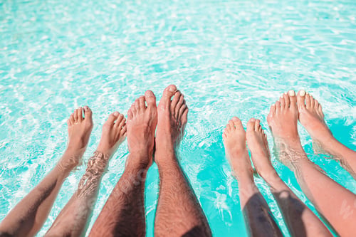 Preview: Close up of four people's legs by pool side