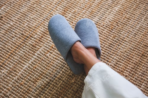Preview: Top view image of a woman with cross legs wearing slippers at home