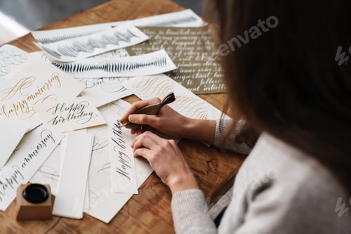 Preview: Focused calligrapher girl writing while working at table