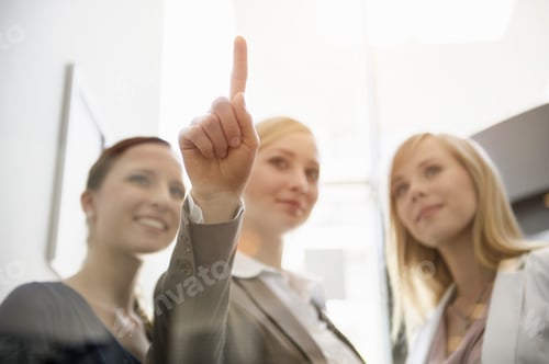 Preview: Businesswomen looking and pointing on glass