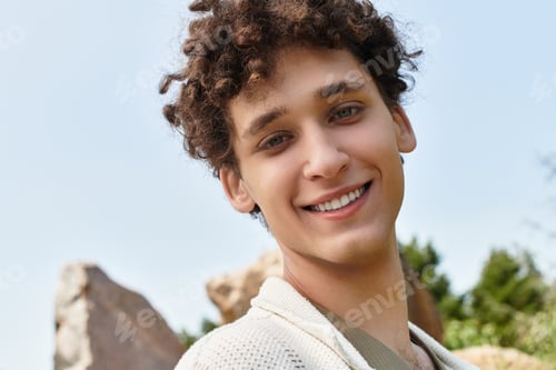 Preview: Young man enjoys a sunny day in a vibrant green park while showcasing summer fashion