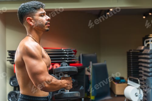 Preview: Young latin man training with dumbbells at the gym