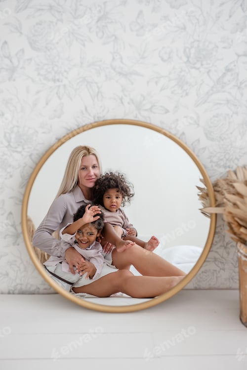 Preview: In round gold mirror, mother sitting on wooden white floor, with African American children laughing