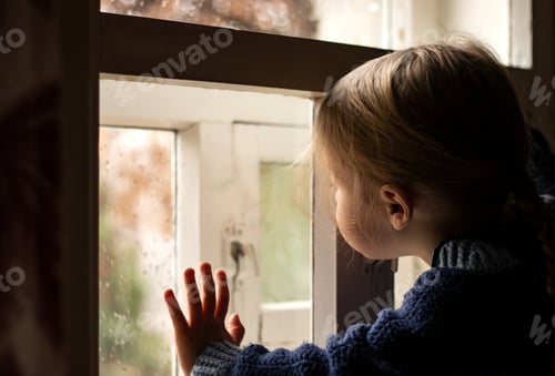 Preview: A little girl looks out the window covered with raindrops