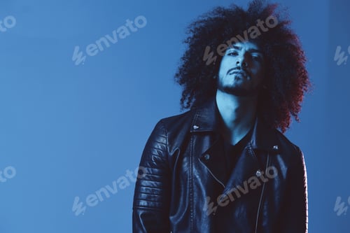 Preview: Portrait of fashion man with curly hair on blue background multinational, colored light, black