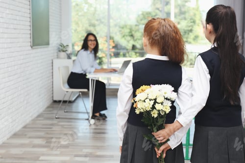 Preview: Schoolgirls with bouquet congratulating their pedagogue in classroom. Teacher's day