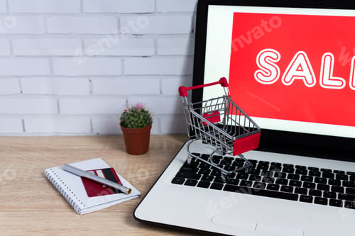 Preview: E-commerce concept. Laptop with red inscription ant toy trolley on wooden table